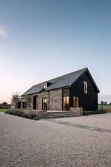 Obraz premium A contemporary house made of stone and wood features a generous driveway, nestled in a tranquil landscape, beautifully illuminated at dusk
