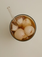Iced lychee tea in a glass with glass straw
