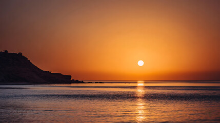 Fototapeta premium Golden sunset over calm ocean with distant rocky coastline water