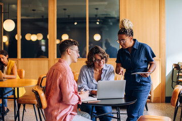 Coworkers collaborating on a project with a laptop in a modern office