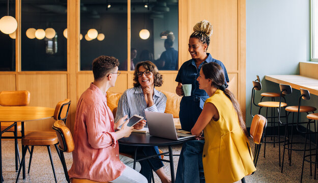 Diverse group of colleagues having a casual discussion in a coworking office - Powered by Adobe