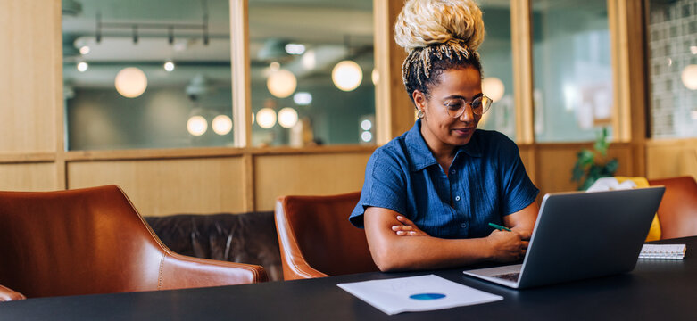 Young woman working on a laptop in a stylish office environment - Powered by Adobe