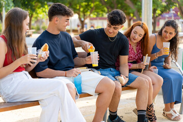 Group of generation z friends enjoying street food and drinks together