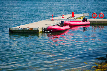 Pink rescue boats moored at dock with visible safety signs