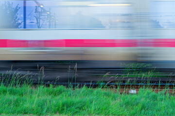Blurred white Deutsche Bahn train speeding past green grass