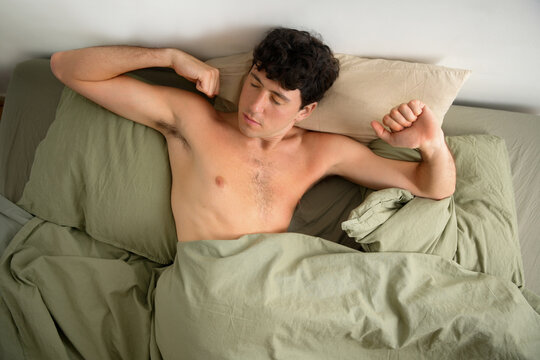 Young man waking up in bed in the morning