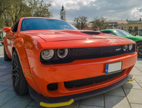 Polska, Ostrowiec Świętokrzyski, 20 lipca 2025, 14:14. Dodge Challenger Hellcat V8 Supercharged na zabytkowej kostce brukowej. Czerwony samoch&oacute;d charakteryzuje się eleganckim, agresywnym designem. 