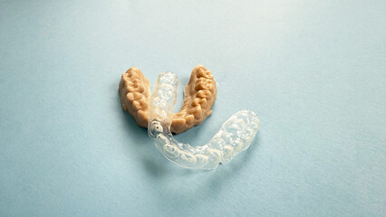 Dental impression of child teeth with transparent worn paediatric mouthguard on blue background,...