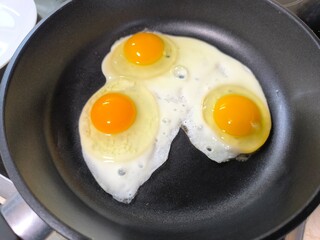 Delicious fried eggs served in a frying pan on a wooden table