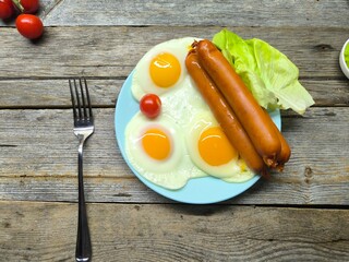 Delicious fried eggs with sausages served on plate on wooden table