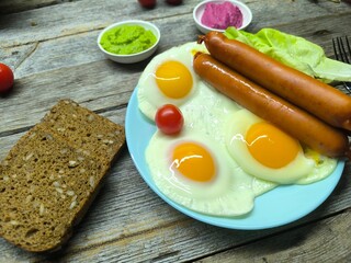 Delicious fried eggs with sausages served on plate on wooden table