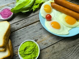 Delicious fried eggs with sausages served on plate on wooden table