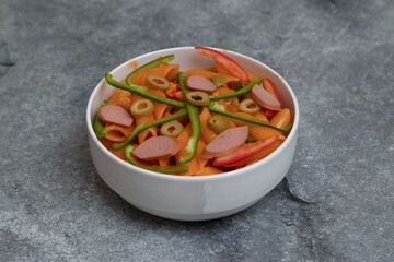 Red Sauce Pasta with Sliced Sausage, Olives and Green Bell Peppers in bowl side view of Italian food