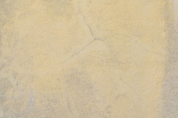 Cracked Yellow Plaster Wall with Rough Texture and Subtle Aging Patterns