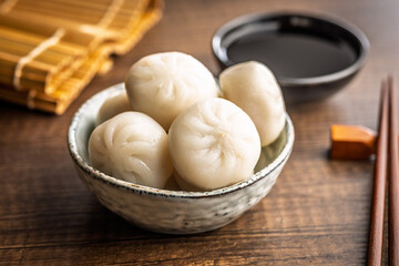 Xiao long bao. Chinese dumplings in bowl on wooden table.