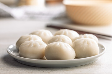 Xiao long bao. Chinese dumplings on plate on kitchen table.