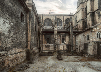 Historic Gothic cathedral courtyard in Asturias, Spain, with weathered stone walls, arched windows,...