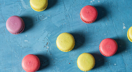 tasty french macaroons on blue background with copy space