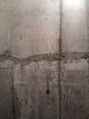 Texture of grey concrete wall with dark water and oil marks running vertically down