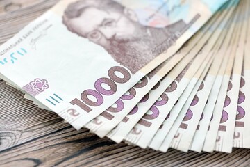 Big amount of ukrainian new one hundred hryvnia money bills with modern design on wooden background. Financial concept, business