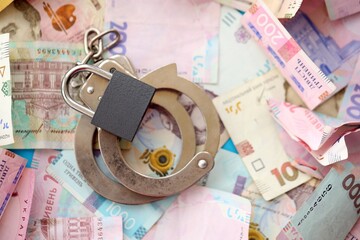 Ukrainian money bills with handcuffs and padlock