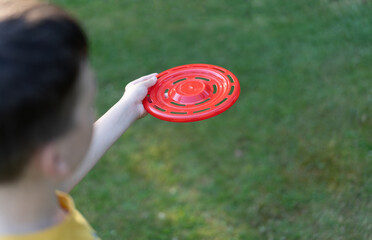A teenager holds a frisbee in his hands.A red flying saucer for outdoor play.
