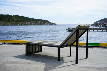 Wooden outdoor lounge chair by the waterfront in a coastal town.
