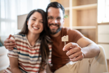Happy couple showing new house key while moving in new home