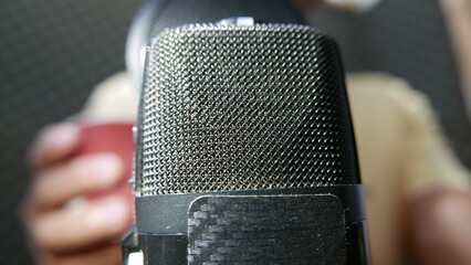 Podcasting: someone recording a podcast in a studio. Someone talking into a microphone. A man...
