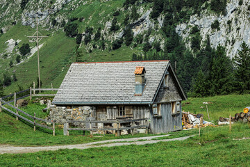 Traditional rustic wooden hut with stone foundation, nestled in the Swiss Alps, surrounded by lush...