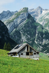 Traditional Swiss alpine house with solar panels on the roof, located on a grassy hillside with...