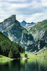Breathtaking view of towering alpine peaks with dramatic rock formations and lush green slopes,...