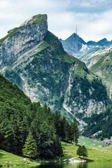 Breathtaking view of towering alpine peaks with dramatic rock formations and lush green slopes,...