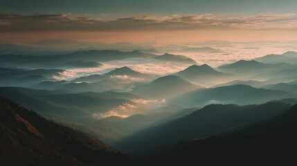 Moody dramatic mountain range with layered fog and warm sunset light.