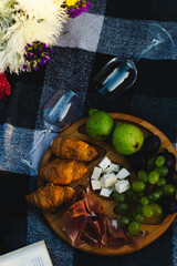 Cozy picnic scene featuring fresh fruits, a book, and delicious croissants arranged on a blanket in...