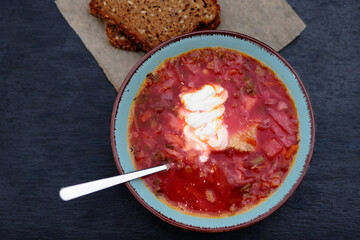 Traditional Ukrainian borscht with beetroot, served with sour cream and slices of rye bread.