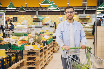 Man pushing shopping cart and buying groceries in supermarket