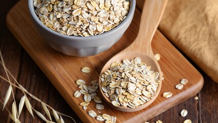 A rustic bowl and wooden spoon filled with rolled oats rest on a wooden cutting board, surrounded by scattered oats and oat stalks—evoking wholesome nutrition, natural ingredients, and cozy kitchen