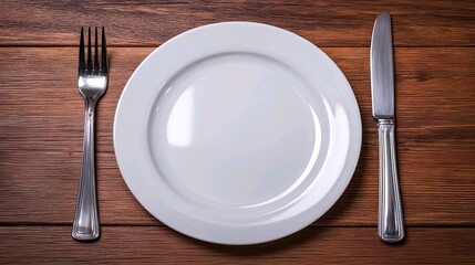 Empty white plate with fork and knife on wooden table &ndash; minimalist food concept