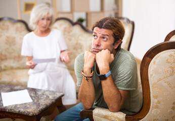 Anxious man doesnt talk to his woman partner at home. Woman trying to discuss important documents...