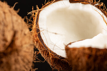 Coconuts placed on a dark surface and black background, low key photo, selective focus.