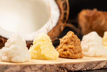 Open coconut and coconut sweets (cocadas) placed on a dark surface, black background, selective focus.