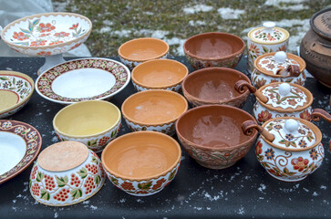 Array of ceramic pottery, including bowls, plates, and lidded jars, adorned with intricate painted...