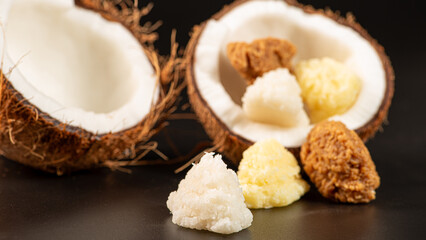 Open coconut and coconut sweets (cocadas) placed on a dark surface, black background, selective focus.