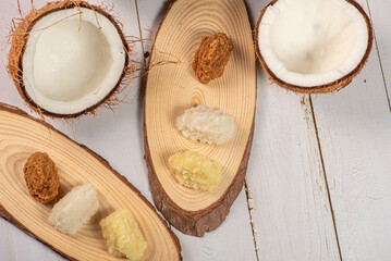 Open coconut and coconut sweets (cocadas) placed on a rustic wooden surface, selective focus.
