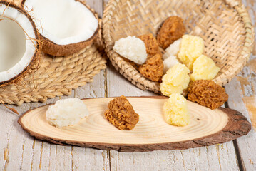 Open coconut and coconut sweets (cocadas) placed on a rustic wooden surface, selective focus.