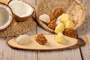 Open coconut and coconut sweets (cocadas) placed on a rustic wooden surface, selective focus.