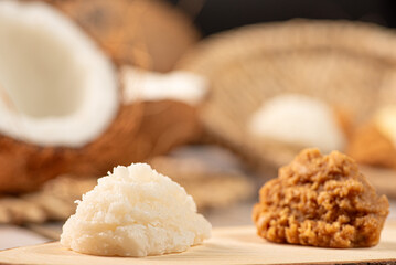 Open coconut and coconut sweets (cocadas) placed on a rustic wooden surface, selective focus.