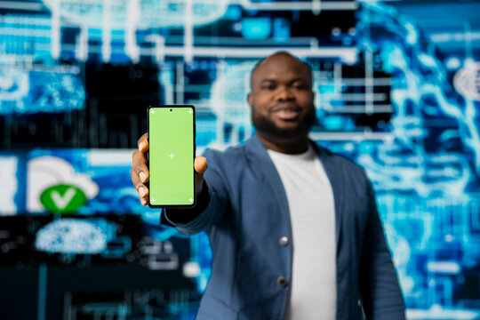 Black businessman using advanced technology and green screen on phone, exploring data science, automation and AI brain in a digital data visualization environment. Machine learning.