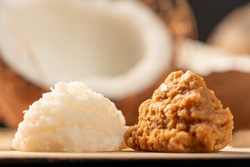 Open coconut and coconut sweets (cocadas) placed on a rustic wooden surface, selective focus.